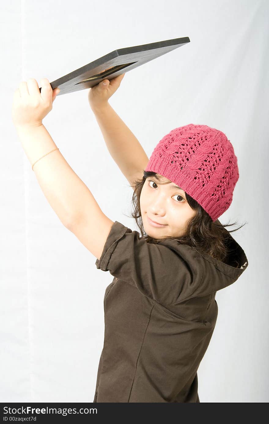 Cute asian girl with pink and red hat holds up a mirror.