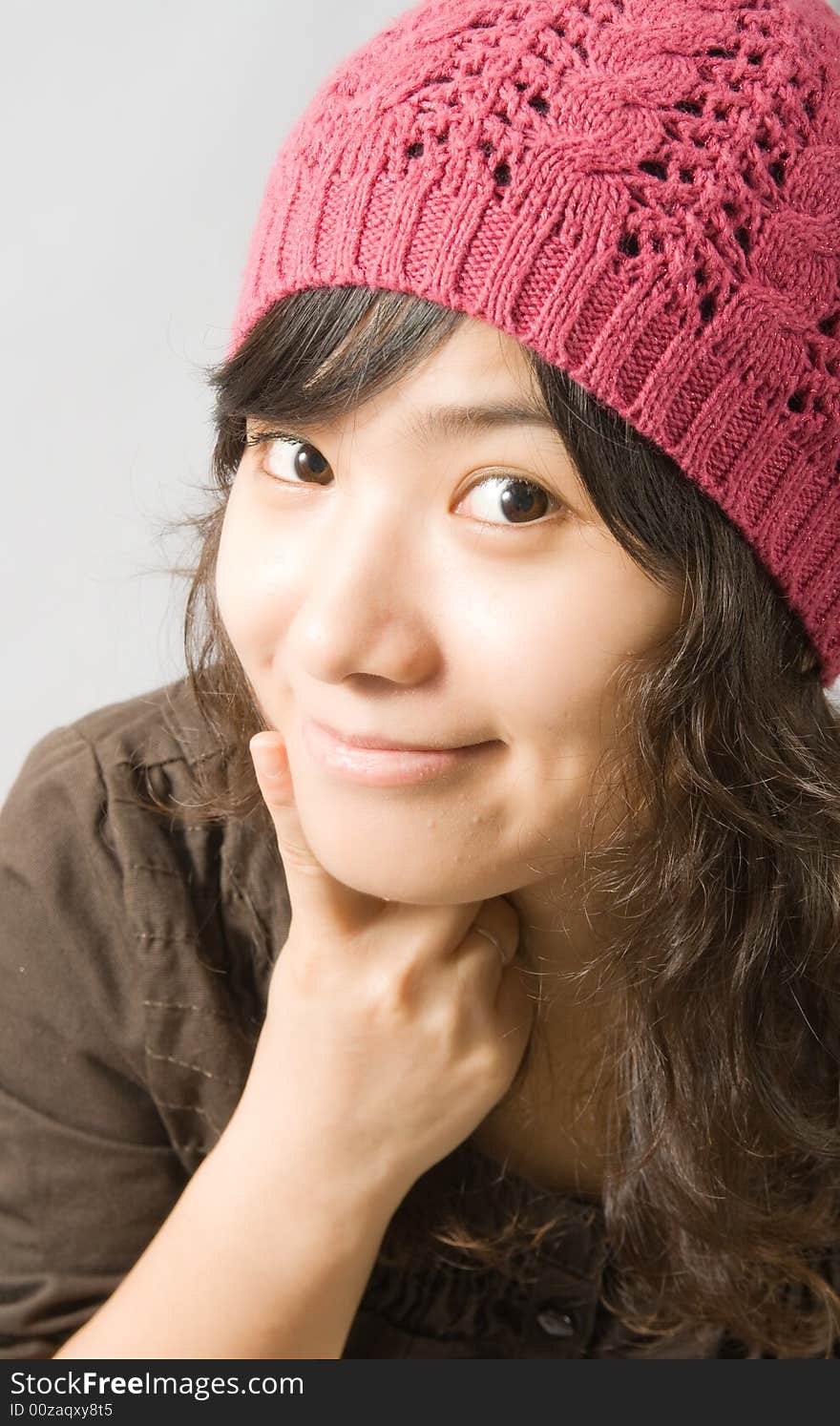 A cute asian girl with a pink hat, pointing to her mouth to offer a sweet smile. A cute asian girl with a pink hat, pointing to her mouth to offer a sweet smile