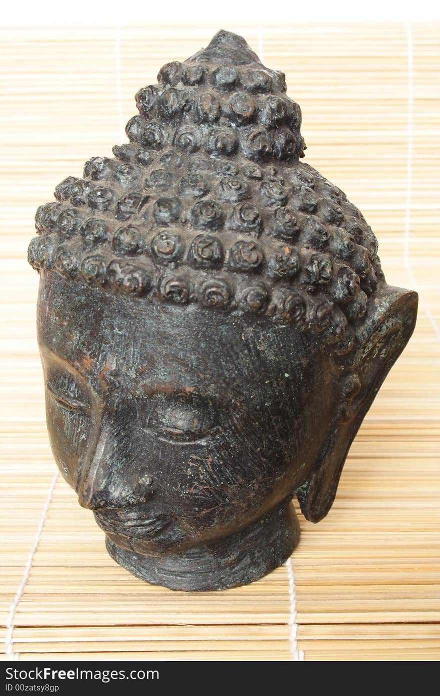 Isolated Buddha head on a wooden mat. Isolated Buddha head on a wooden mat