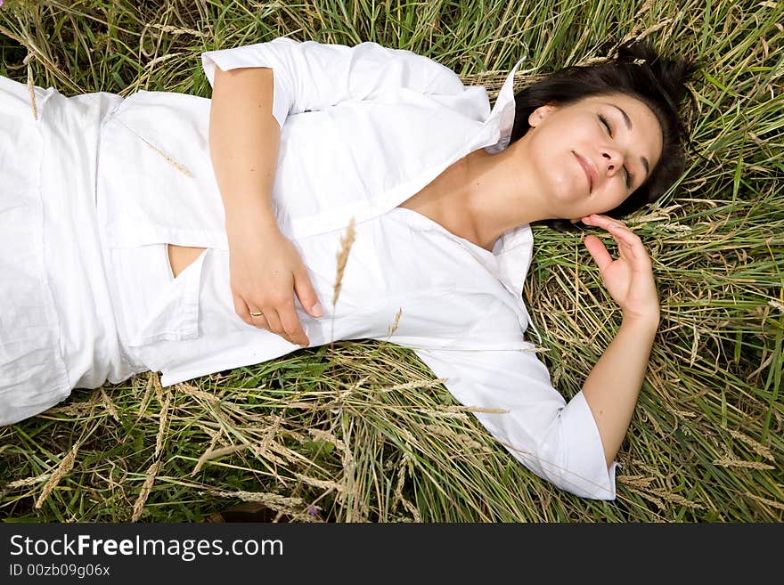 Attractive brunette woman relaxing on  meadow. Attractive brunette woman relaxing on  meadow