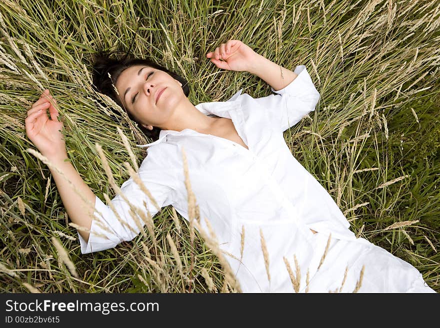 Attractive brunette woman relaxing on  meadow. Attractive brunette woman relaxing on  meadow