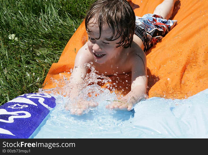 A small boy going down a waterslide. A small boy going down a waterslide