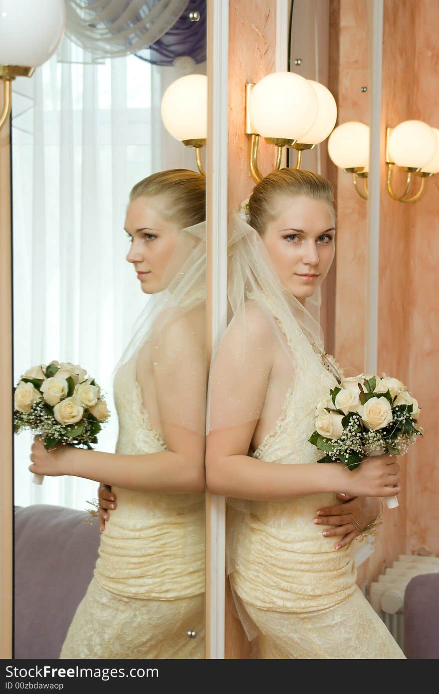 The bride with a bouquet of roses, near a mirror. The bride with a bouquet of roses, near a mirror