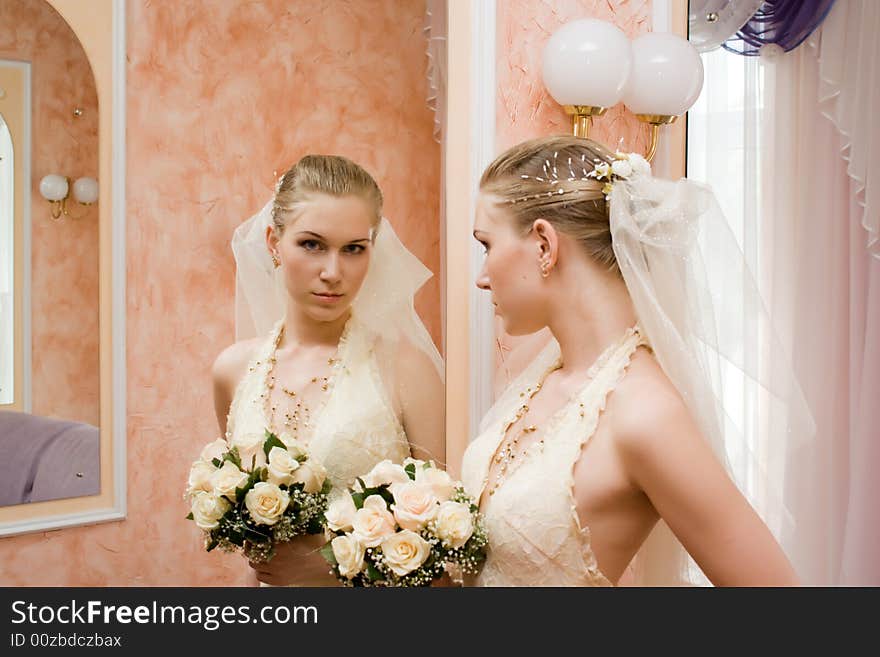 The bride with a bouquet of roses, near a mirror. The bride with a bouquet of roses, near a mirror