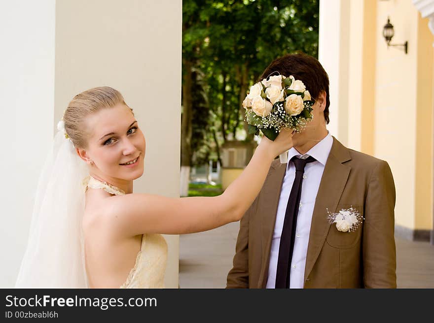 The bride closes a face of the groom a bouquet. The bride closes a face of the groom a bouquet