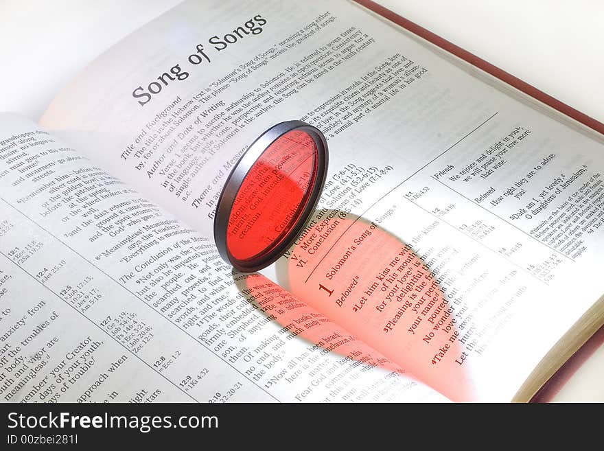 Holy Bible with a red heart (as a reflection of a red filter) on pages of the Song of Songs