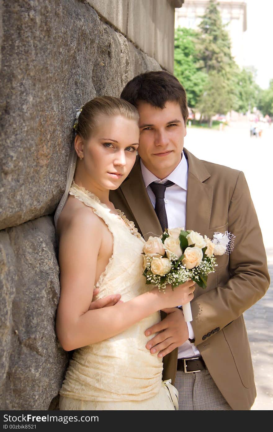 Newly-married couple near a stone wall