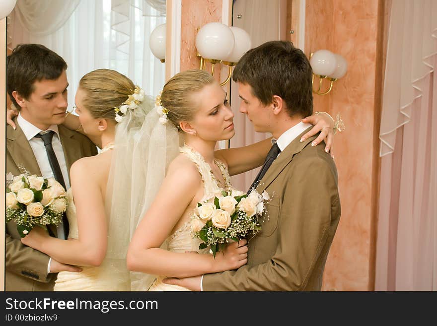 Newly-married couple embraces near a mirror