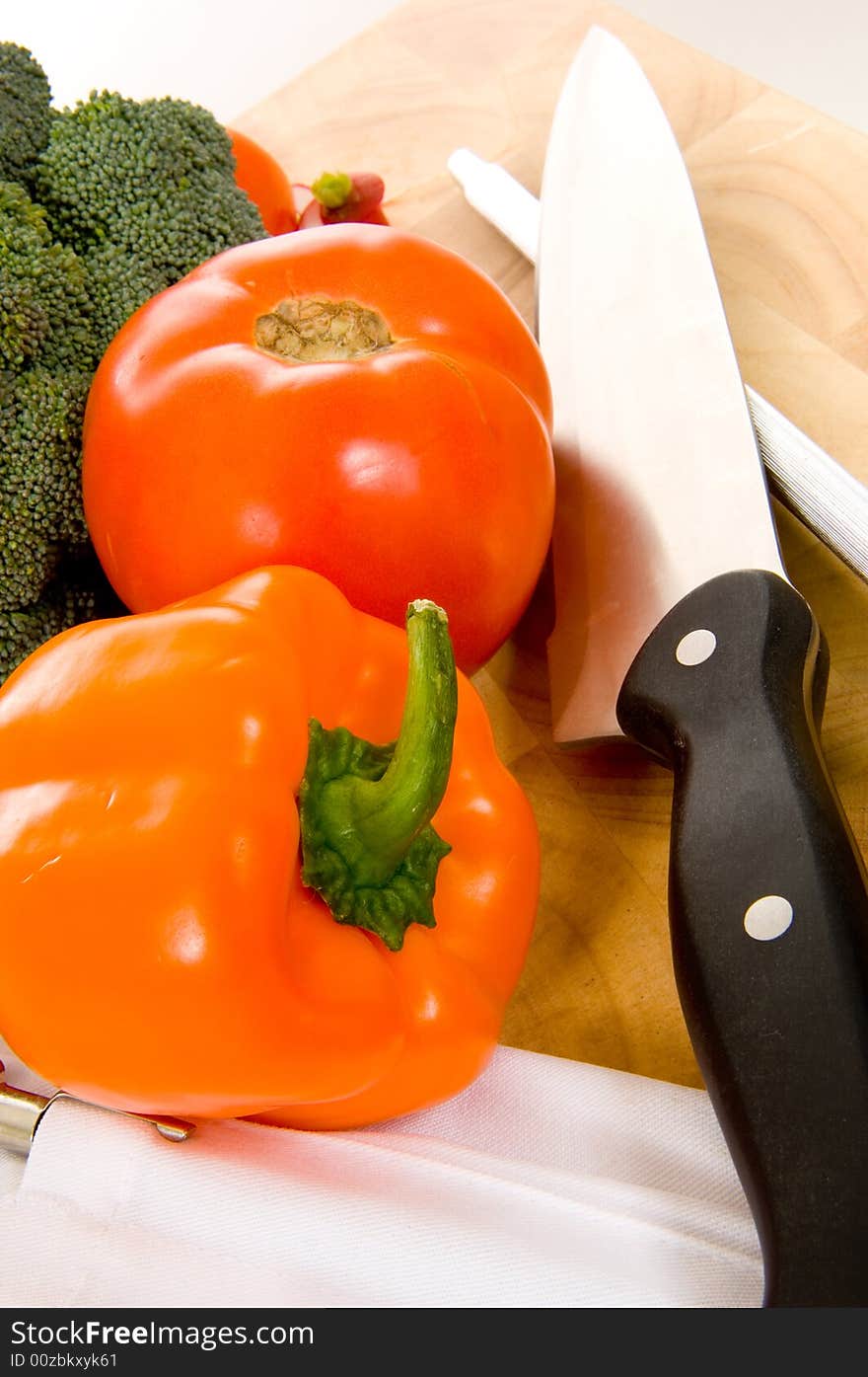 Assorted fresh vegetables on cutting board with chefs - cooks knife