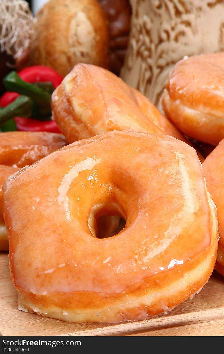 Stack of fresh baked glazed donuts in kitchen or restaurant.