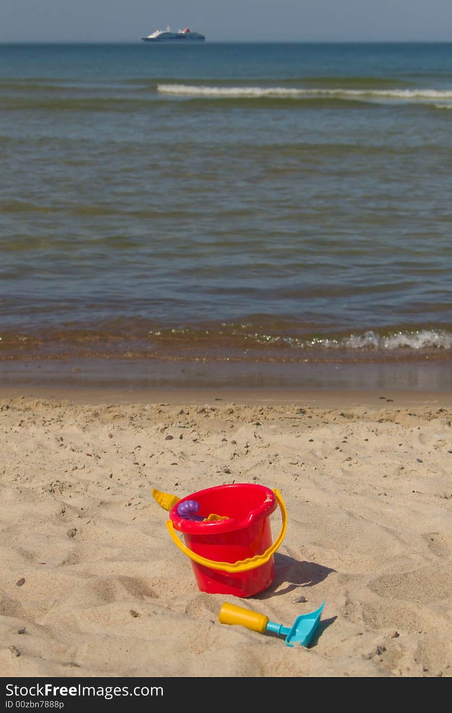 Plastic beach toys and cruise ship on horizon. Plastic beach toys and cruise ship on horizon