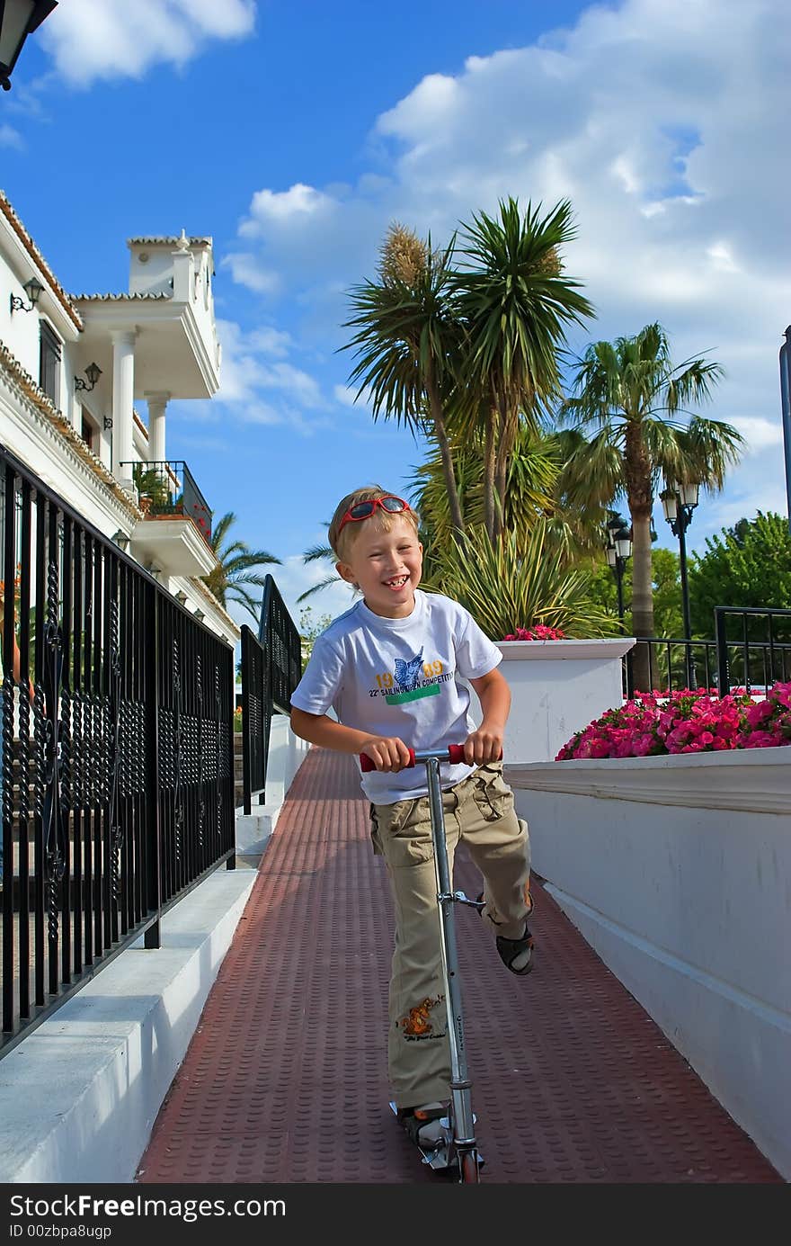 The cheerful boy goes on a scooter en park