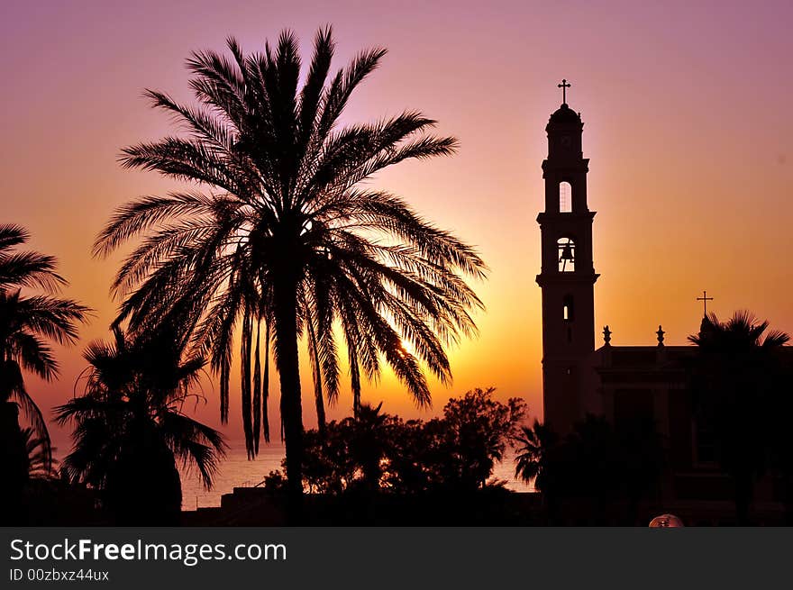 Silhouettes of bell tower and palm on background of sunset sky. Silhouettes of bell tower and palm on background of sunset sky