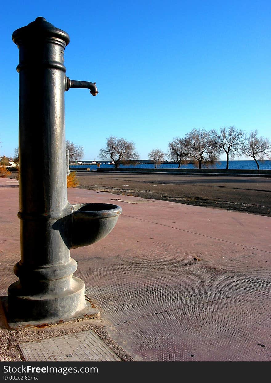 A small water fountain not working anymore on a pavement along the beach