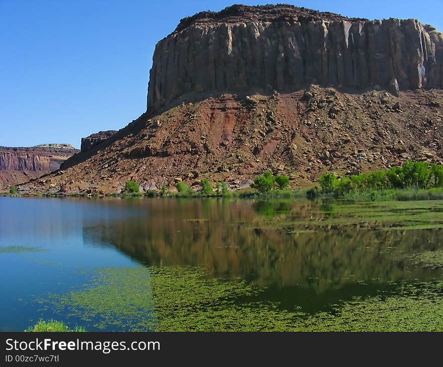 A sandstone mesa reflection in the waters of a small river, near Canyonlands National Park, Moab, Utah. A sandstone mesa reflection in the waters of a small river, near Canyonlands National Park, Moab, Utah.