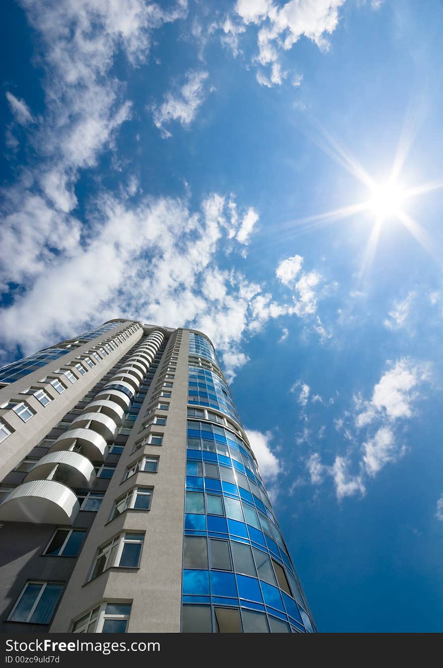 Tall office or residental building on blue sky with clouds. Wide-angle lens used. Tall office or residental building on blue sky with clouds. Wide-angle lens used.