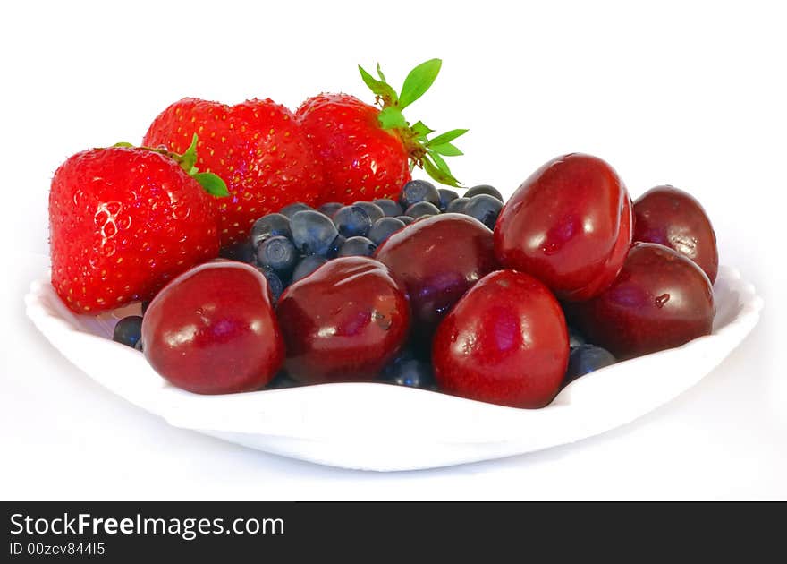 Fresh strawberries, bilberries and sweet cherry in white saucer. Fresh strawberries, bilberries and sweet cherry in white saucer