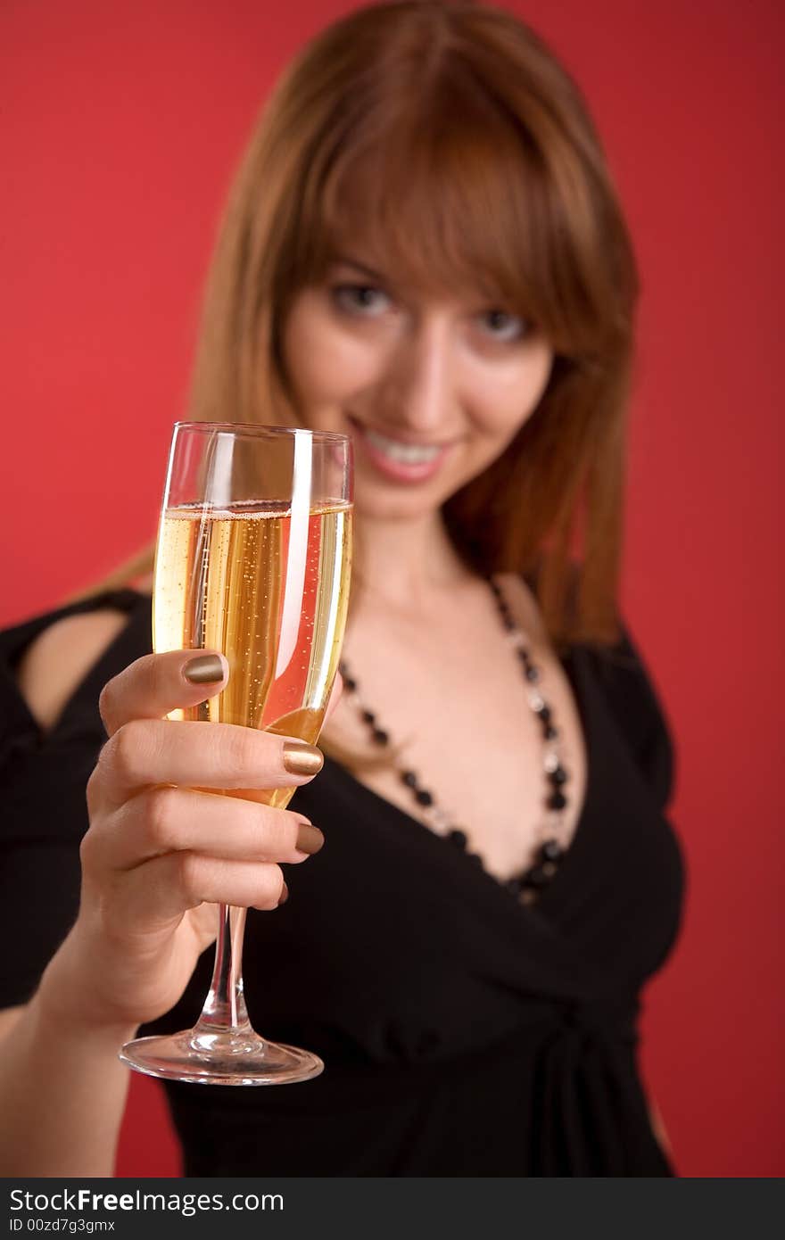 Girl with champagne, focus on glass isolated on red background