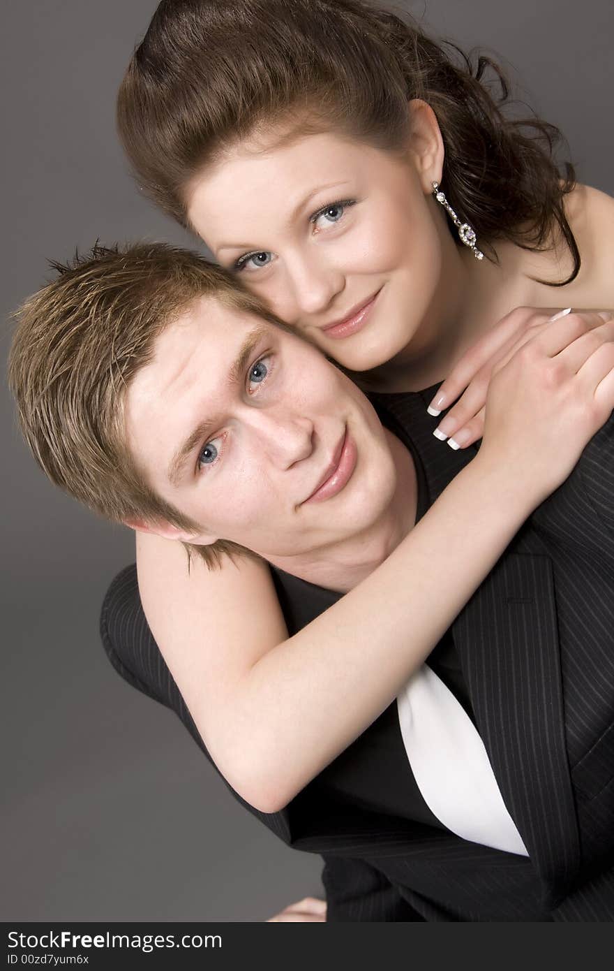 Portrait of a young beautiful couple embracing. (gray background)