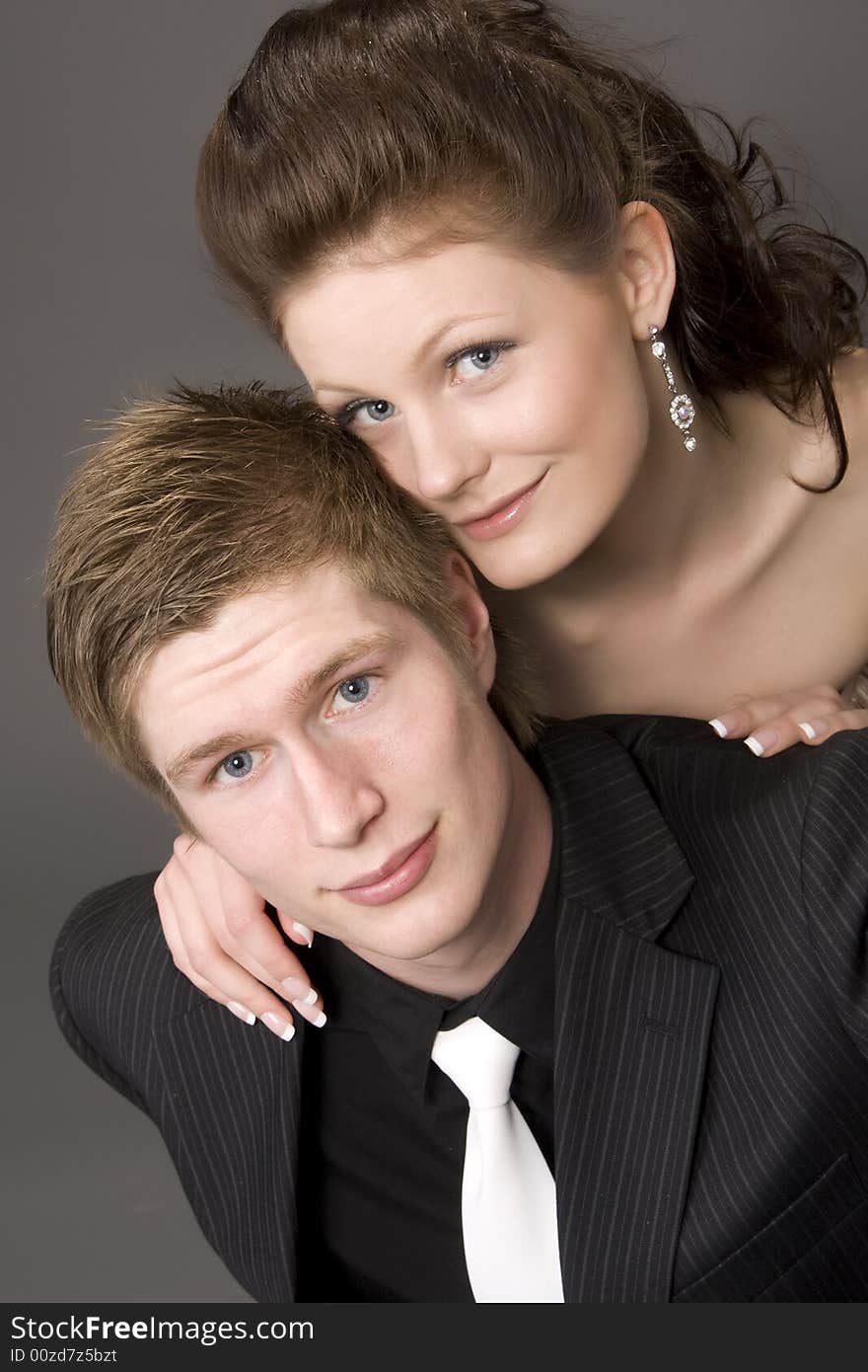 Portrait of a young beautiful couple embracing. (gray background)