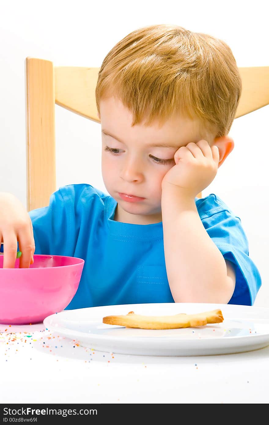 A moodly three year old in a blue top with a biscuit and sweets. A moodly three year old in a blue top with a biscuit and sweets