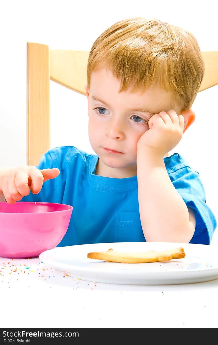 A moodly three year old in a blue top with a biscuit and sweets and a distant expression. A moodly three year old in a blue top with a biscuit and sweets and a distant expression