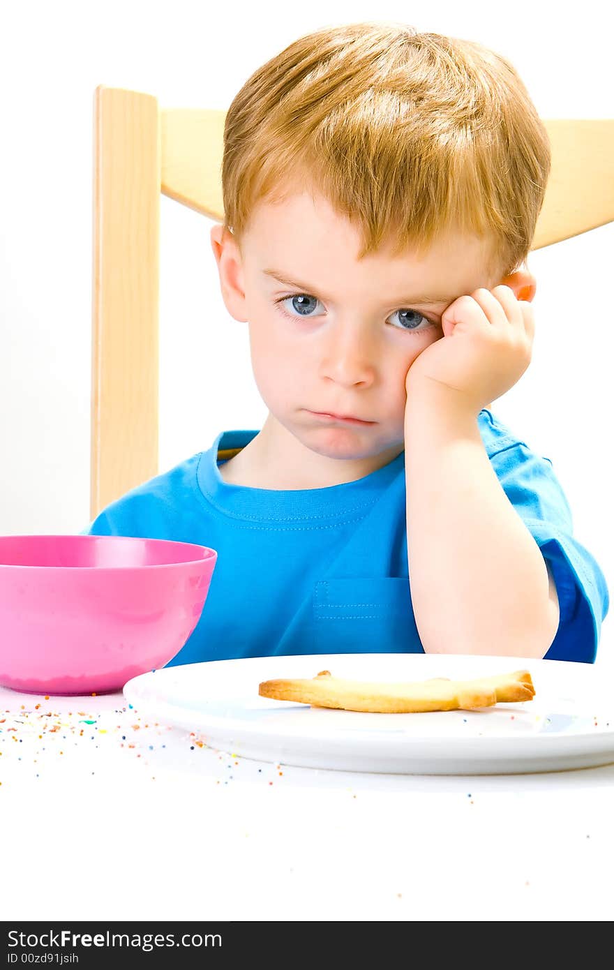 A moodly three year old in a blue top with a biscuit and sweets and an annoyed expression. A moodly three year old in a blue top with a biscuit and sweets and an annoyed expression