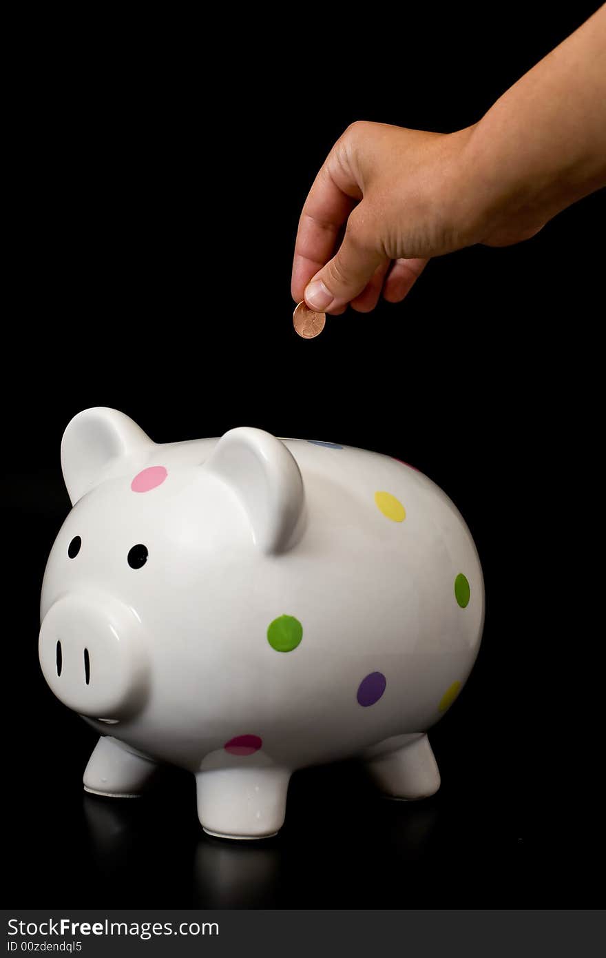 Ceramic piggybank and penny on black background