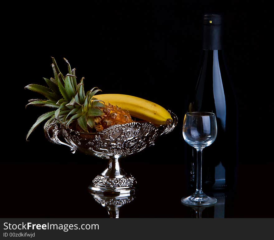 Vase with fruit, a bottle and a glass on a black background. Vase with fruit, a bottle and a glass on a black background