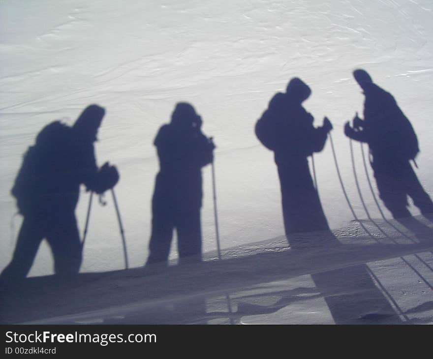 The person who photographes shadows of the friends on a snow in mountains. The person who photographes shadows of the friends on a snow in mountains.