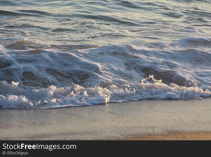 Small waves strike the surface of the sand at dusk. Small waves strike the surface of the sand at dusk.