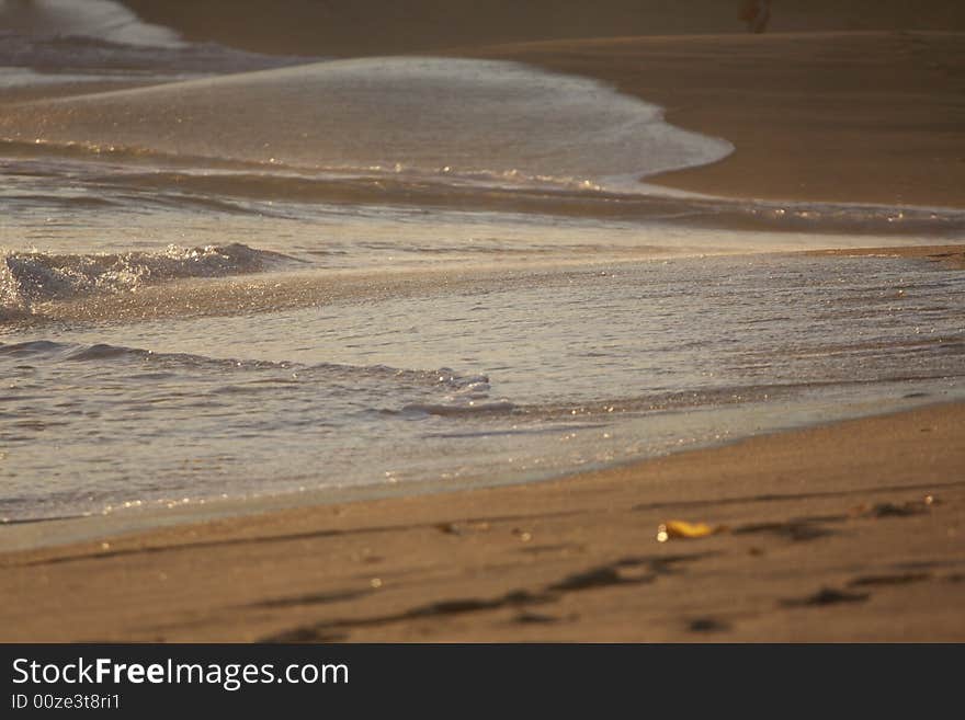 Small waves strike the surface of the sand at dusk. Small waves strike the surface of the sand at dusk.