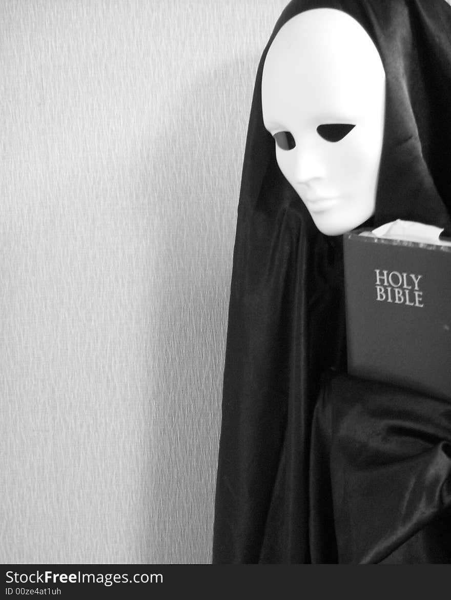 A black and white image of a masked image holding a bible. A black and white image of a masked image holding a bible.