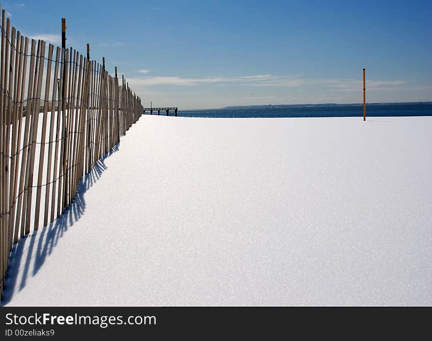 Fence, snow, post and dark blue ocean