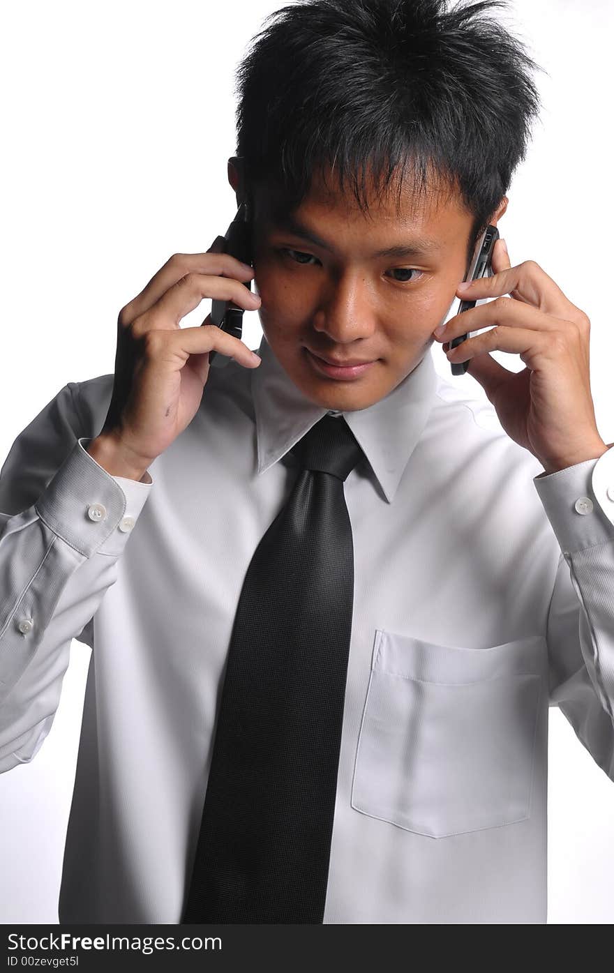 Asian business man conversing with multiple handphones. Asian business man conversing with multiple handphones