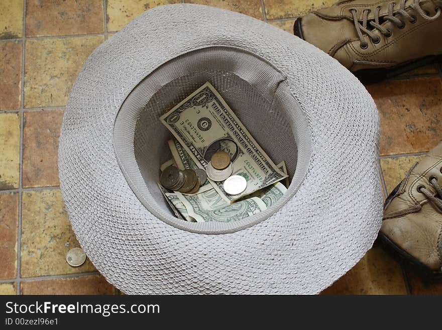 Beggar's hat with money lying on pavement