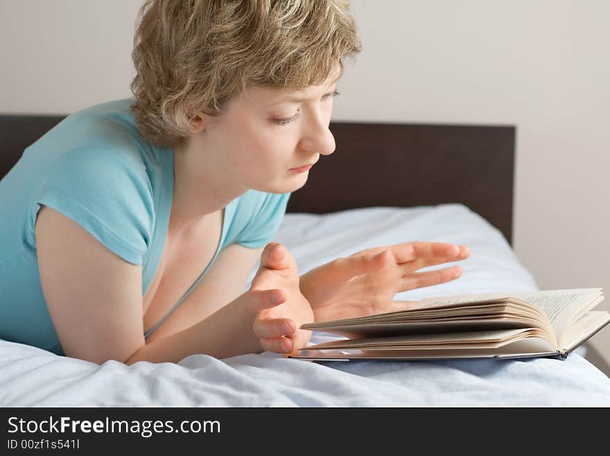 Young woman reading book on a bed, shallow DOF, focus on eyes. Young woman reading book on a bed, shallow DOF, focus on eyes