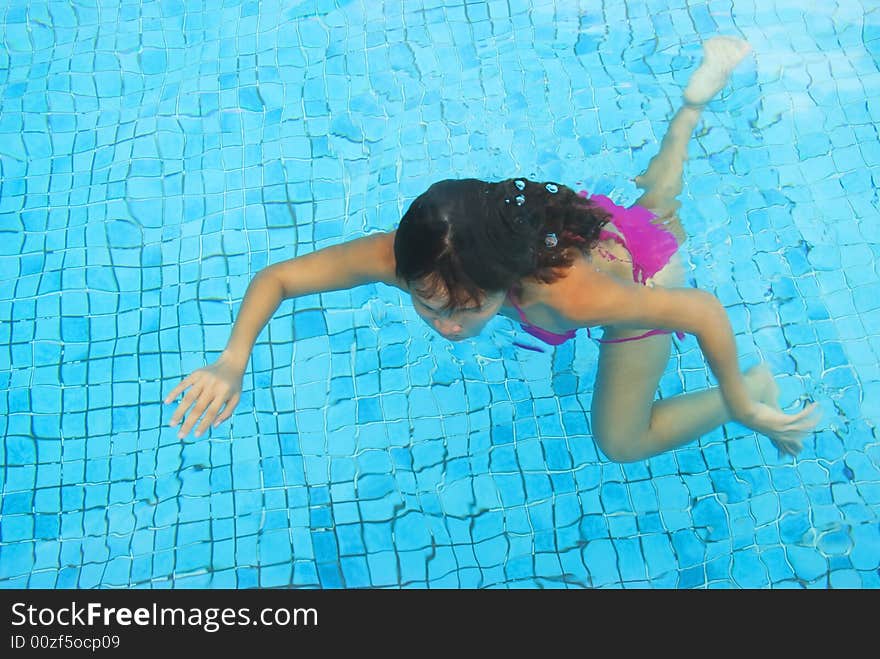 A young woman wearing a pink bikini swimming in a pool. A young woman wearing a pink bikini swimming in a pool