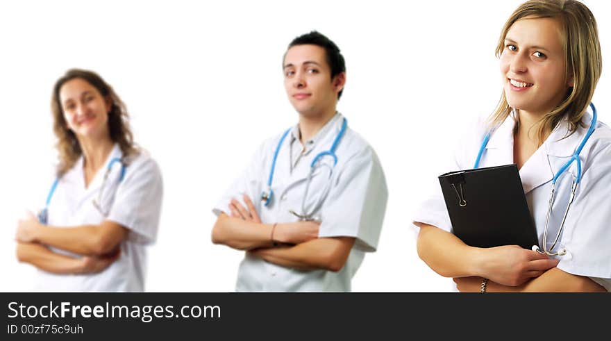 An attractive female surgeon is holding some medical records. Behind her there are two other surgeon colleagues. They have stethoscopes and they are wearing white coats. An attractive female surgeon is holding some medical records. Behind her there are two other surgeon colleagues. They have stethoscopes and they are wearing white coats.