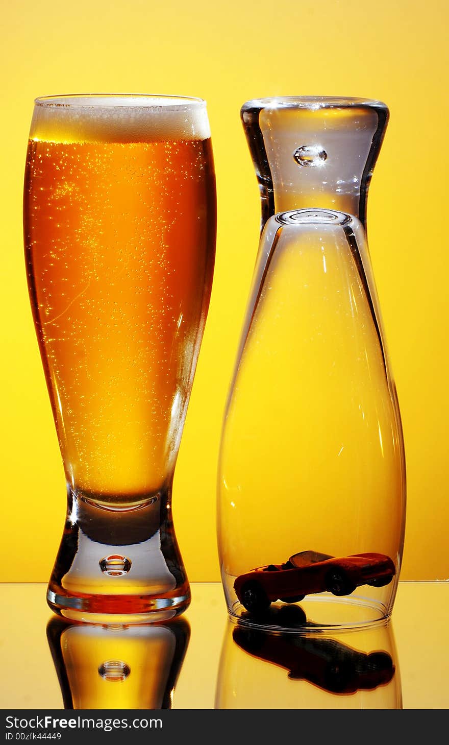 Close-up of glass of beer and upside down glass covering small car. Close-up of glass of beer and upside down glass covering small car