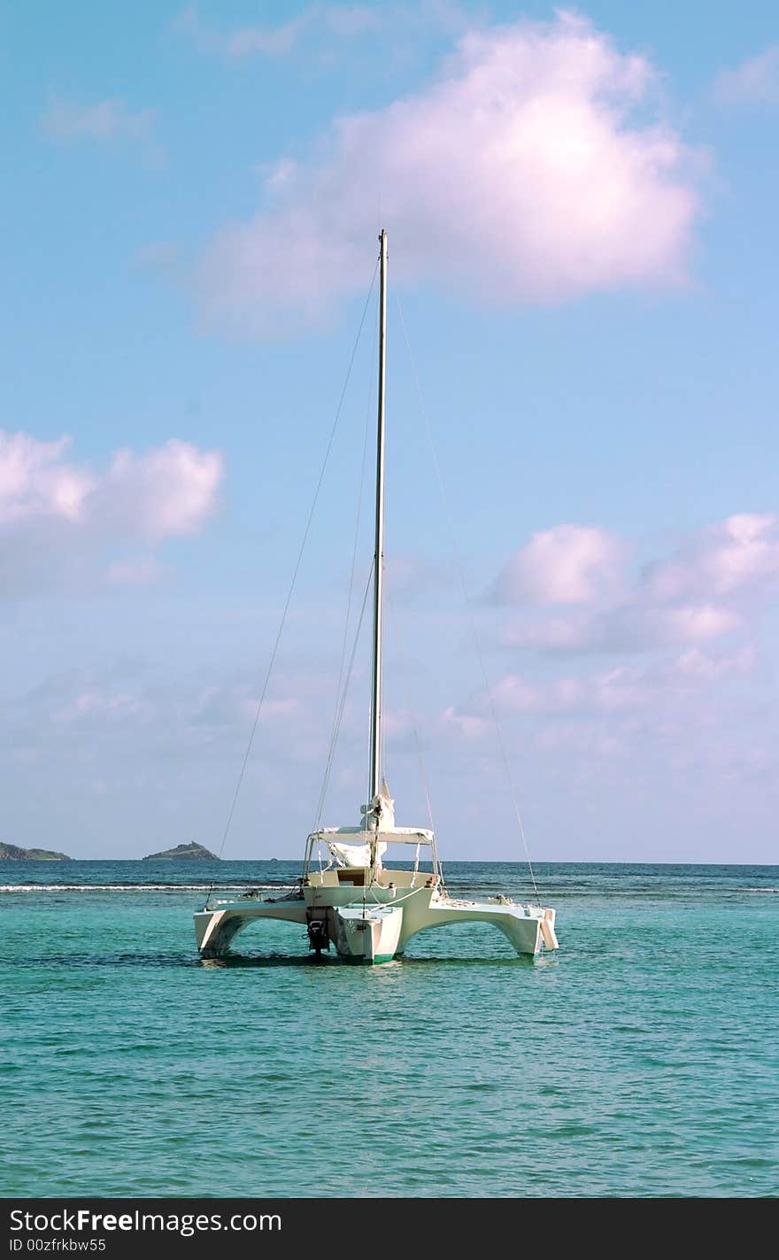 A Trimaran sailboat anchored in the bay of a paradise island setting. A Trimaran sailboat anchored in the bay of a paradise island setting.