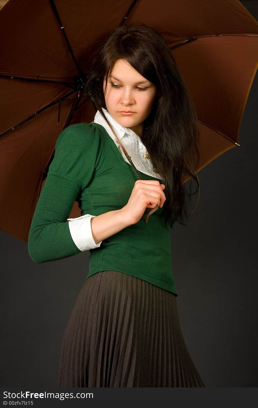 Serious looking girl in green sweater holding umbrella