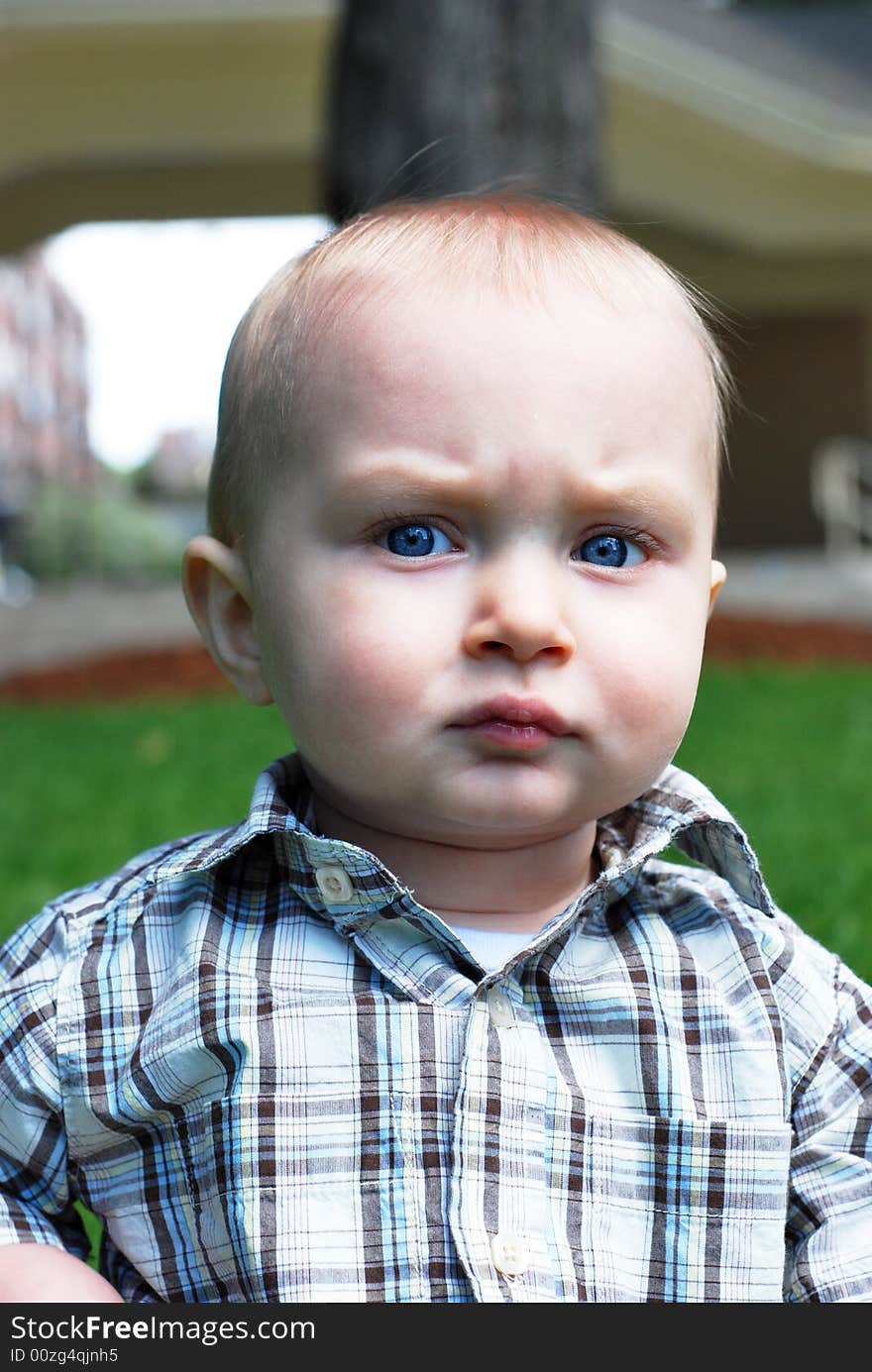 A young child gives off an intense, almost threatening, look at the camera in a park. - vertically framed. A young child gives off an intense, almost threatening, look at the camera in a park. - vertically framed