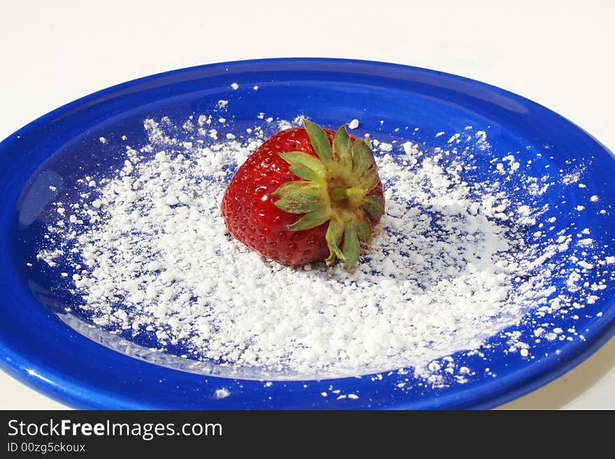 Single strawberry on blue plate with powdered sugar on white background. Single strawberry on blue plate with powdered sugar on white background