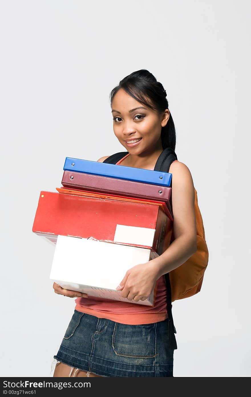 Overwhelmed female student wearing a backpack carries notebooks and papers. Vertically framed photograph. Overwhelmed female student wearing a backpack carries notebooks and papers. Vertically framed photograph.