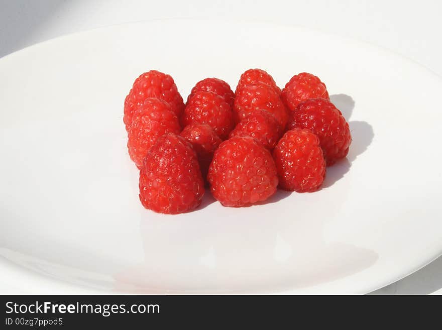 Many raspberries on white plate