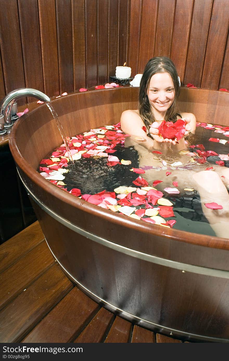 A young girl in a tub of water, holding various rose petals. - vertically framed. A young girl in a tub of water, holding various rose petals. - vertically framed