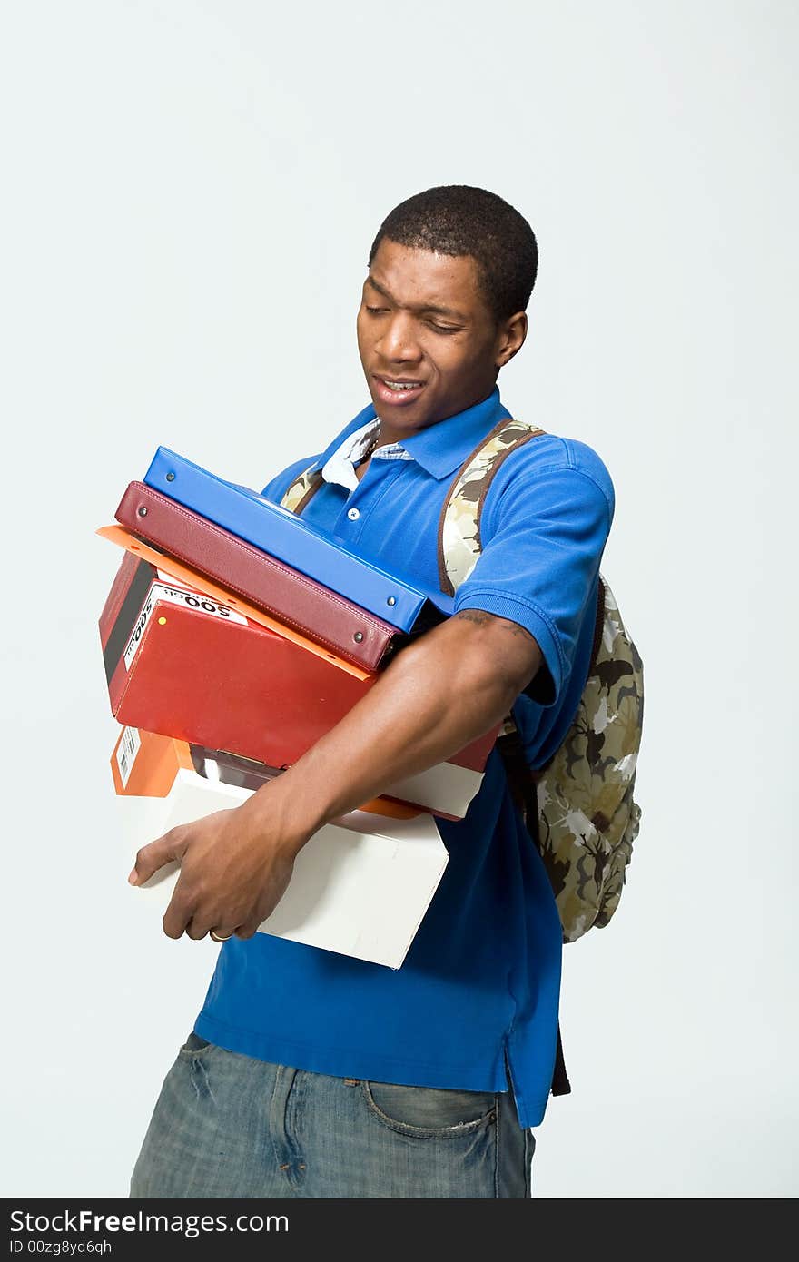 Male student wearing a backpack carries notebooks and boxes. He looks frustrated. Vertically framed photograph. Male student wearing a backpack carries notebooks and boxes. He looks frustrated. Vertically framed photograph.