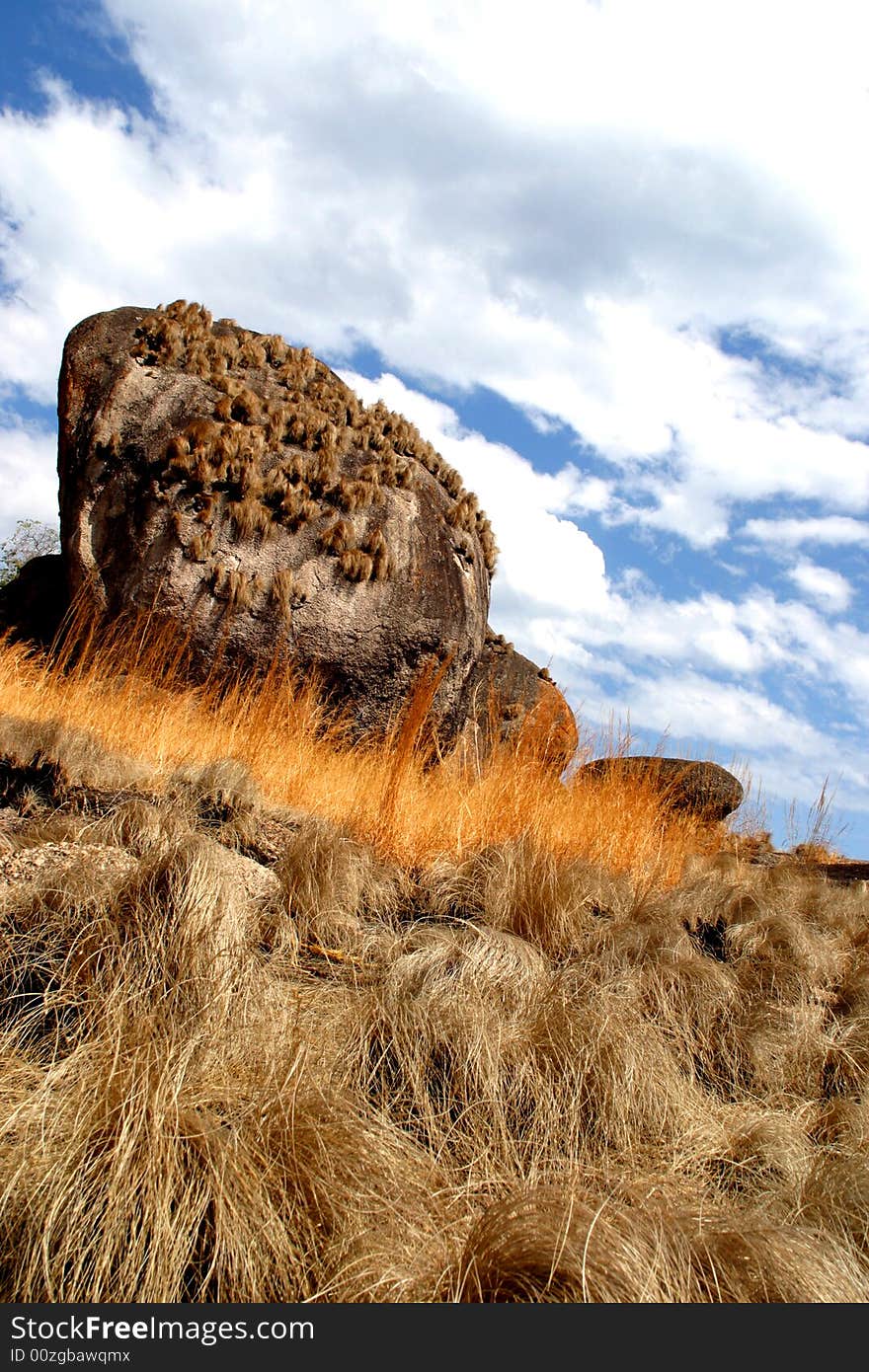 Big rock under the sky on blades of grass