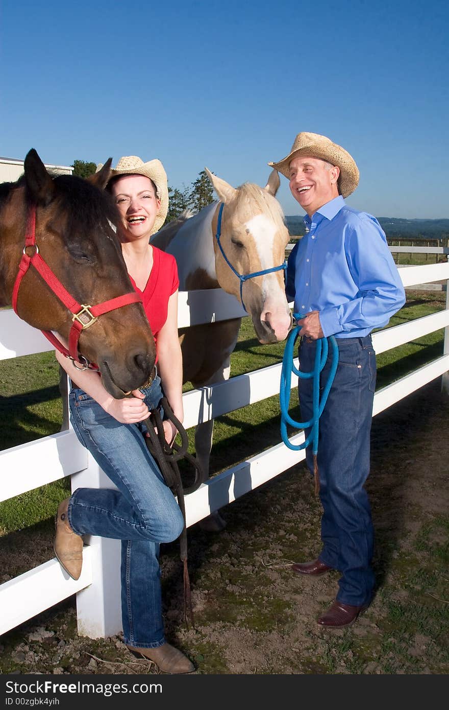 Couple in Cowboy Hats With Horses - Vetical